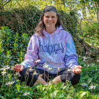 woman sitting on the ground in fawn lilies with a HAPPY hoodie on